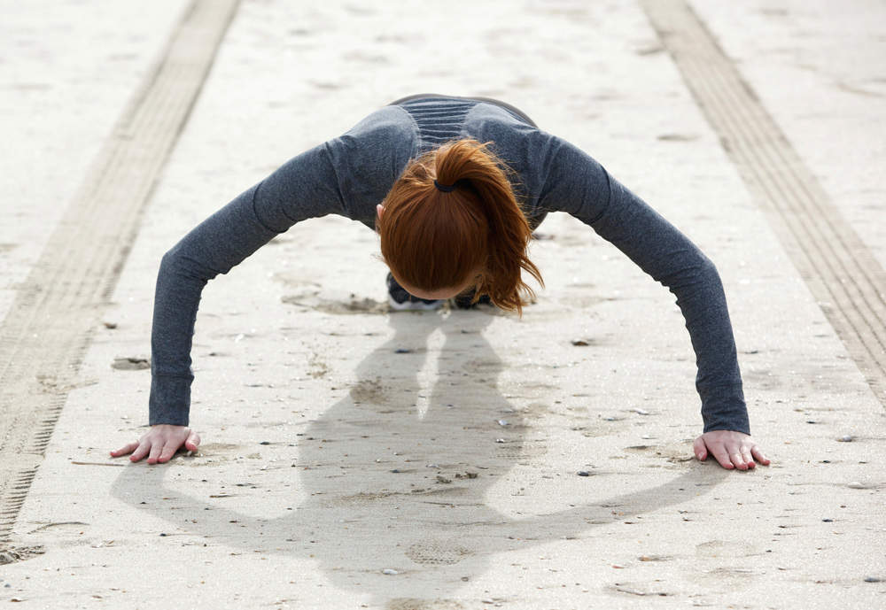 Woman doing pushups on sand